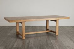 a wooden table sitting on top of a hard wood floor next to a white wall