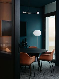 a dining room table with four chairs and a lamp on the wall next to it