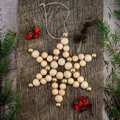 an ornament made out of eggs and bells on a wooden board surrounded by pine branches