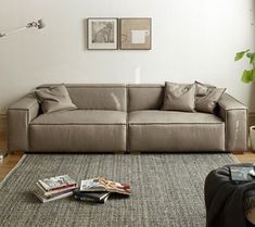 a living room filled with furniture and pillows on top of a gray rug next to a window