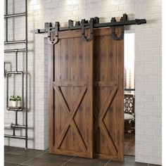 an open wooden door with metal hardware on the top and bottom, in front of a brick wall