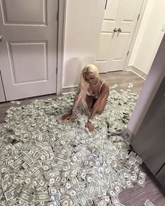 a woman kneeling on the floor covered in money