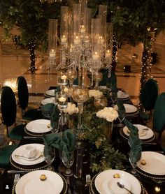 the table is set with white plates, silverware and green napkins on it