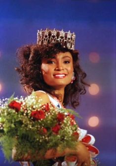 a woman in a tiara holding flowers and smiling