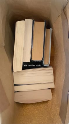 several books are sitting in a brown paper bag on top of each other, one is open and the other two are closed