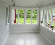 an empty room with white walls and wood flooring, two windows are open to the yard