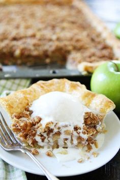 a piece of pie on a plate with ice cream and an apple in the background