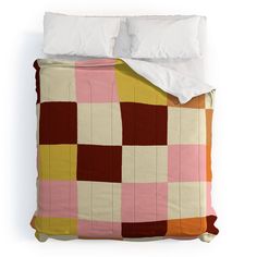 a bed with a pink, yellow and brown checkered comforter on top of it