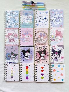 several notebooks are lined up on a white sheet with hello kitty stickers all over them