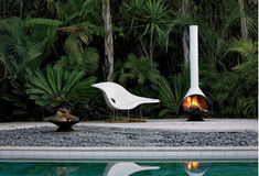 two white chairs sitting next to a pool with a fire in the middle of it