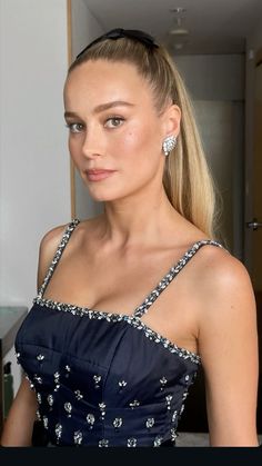 a woman in a blue dress is posing for the camera with her hair pulled back