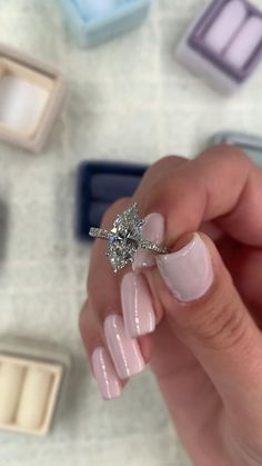 a woman's hand holding an engagement ring with pink acrylic on it