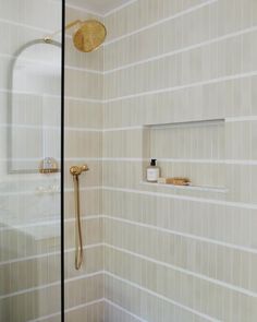 a white tiled bathroom with gold fixtures