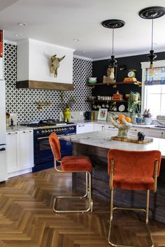 a kitchen with orange chairs and an island in front of a stove top oven next to a window