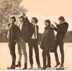 an old black and white photo of four people on a skateboard with trees in the background