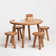 a wooden table with three stools and a book on top of it in front of a white background