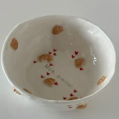 a white bowl with red hearts on the side and words written in it that read home