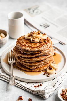 a stack of pancakes on a plate with bananas and walnuts