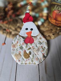 a chicken ornament hanging from a basket on a wooden table next to eggs