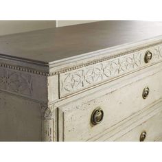 an antique white dresser with ornate carvings on the top and drawers, painted in gray