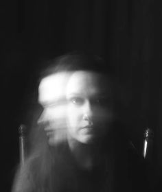 a blurry photo of a woman sitting in a chair with her head turned to the side