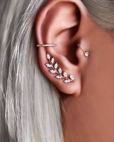 a woman with blonde hair wearing a gold ear cuff and white diamond leaves on the back of her ear