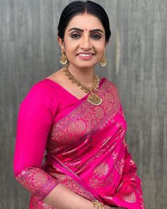 a woman wearing a pink sari and gold jewelry