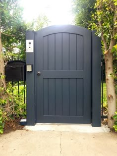 a blue gate is open in front of some trees