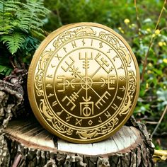 a gold coin sitting on top of a tree stump in front of some plants and trees