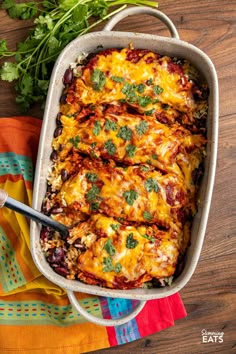 a casserole dish filled with mexican food and garnished with cilantro