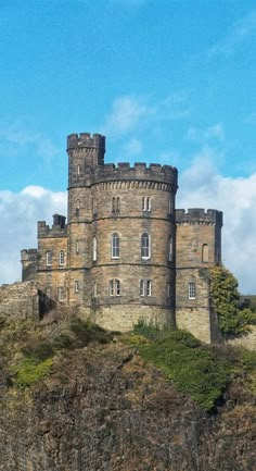 an old castle sitting on top of a hill next to a cliff under a blue sky