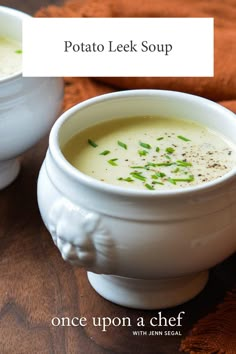 two white bowls filled with soup on top of a wooden table