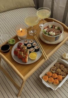 a tray with sushi and drinks on it next to a bowl of soup, two glasses of wine