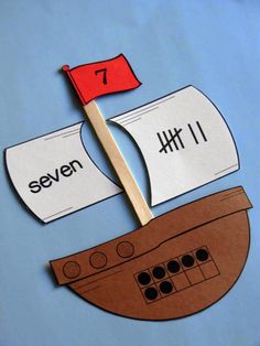 a paper cut out of a boat with the number seven on it and a red flag