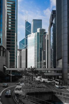 a city with tall buildings and cars driving down the road in front of it,