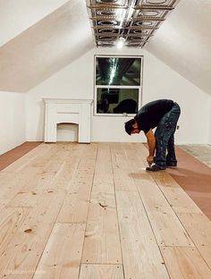 a man kneeling down on top of a hard wood floor in an empty room next to a window