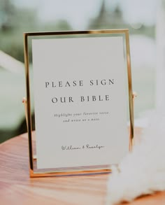 a sign that says please sign our bible on it sitting on top of a wooden table