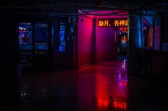 an empty hallway with neon lights and signs on the walls in chinese characters are lit up