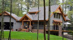 a large house in the woods with lots of trees and grass on the side of it