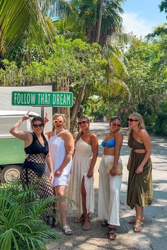 four women standing in front of a green and white sign that says follow that dream