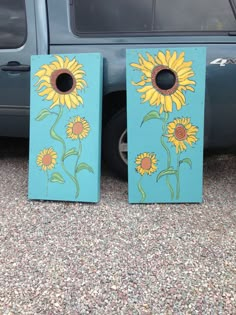 two sunflowers painted on wooden boards next to a car