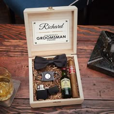 an open wooden box with liquor, cigars and other items in it on a table