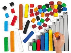 a child's hand is playing with legos and building blocks on a white background