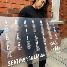 a woman standing in front of a brick wall holding up a sign with words on it