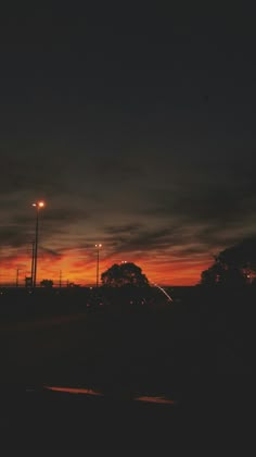 the sun is setting behind some power poles and lights in the distance, with trees on either side