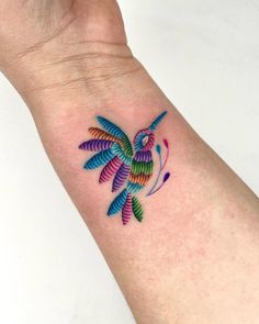 a colorful bird tattoo on the wrist