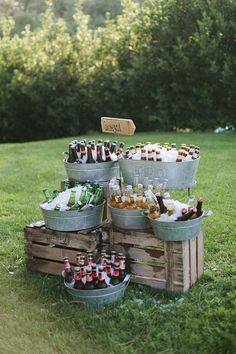 several buckets filled with beer sitting on top of a grass covered field next to trees