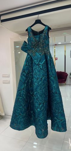 a teal dress hanging on a hanger in a room with white tile flooring