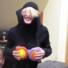 a woman with blonde hair wearing a black outfit and holding two balls in her hands