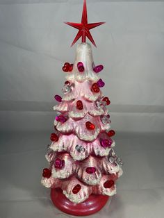 a small pink christmas tree with red and white ornaments on it's top, in front of a white background